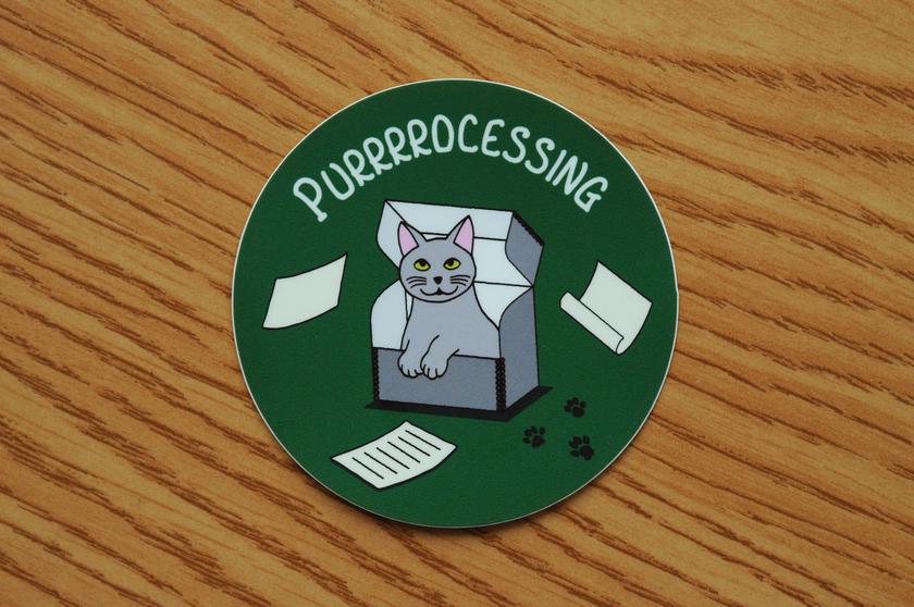 Vinyl sticker with smiling kitty sitting in an archival box with the lid open. The caption says Purrrrocessing.